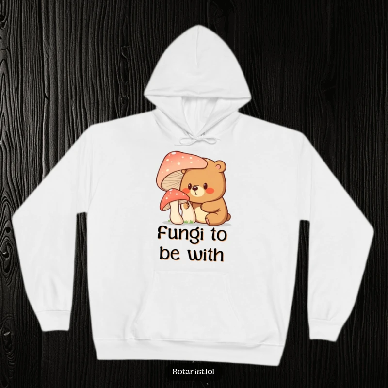 Funny bear with a curious expression investigating a giant mushroom, designed for this cozy and humorous hoodie.
