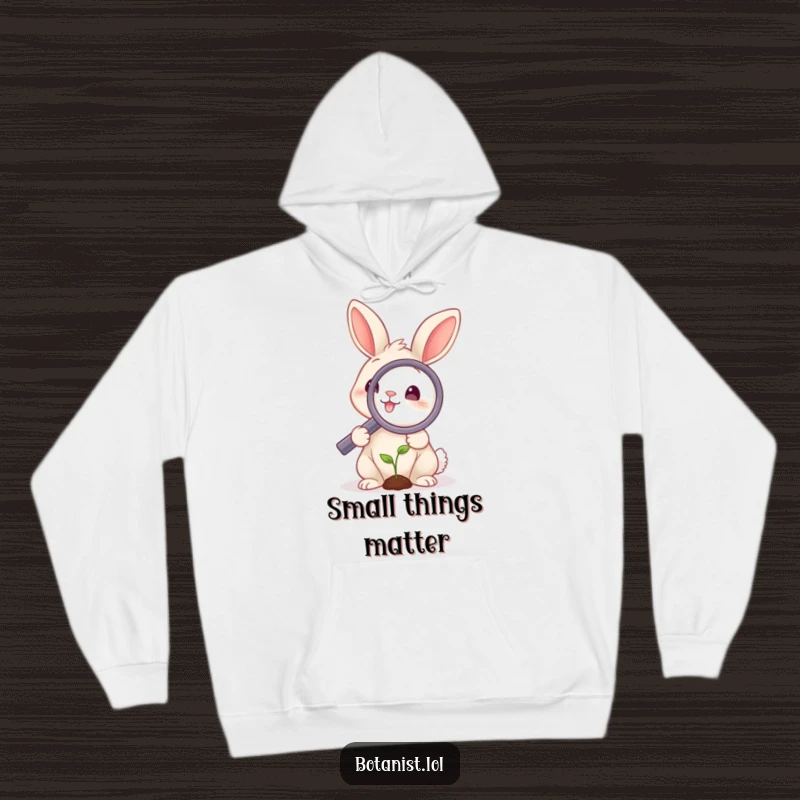 Funny rabbit hoodie featuring a smiling rabbit using a magnifying glass on a tiny sprout, offering comfort and a touch of whimsical intellect.